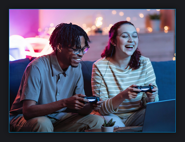 image of girl and boy sitting on a couch playing video games on a laptop
