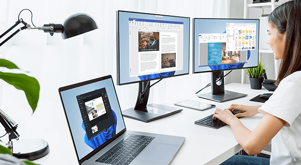 Woman working in front of three displays.